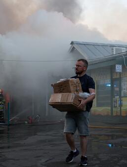 Un homme transporte des cartons contenant des objets récupérés sur le marché aux livres ravagé par un incendie